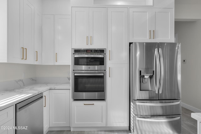 kitchen with white cabinets, stainless steel appliances, and light stone counters