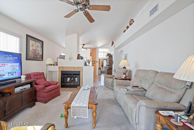 living room with a tiled fireplace, ceiling fan, plenty of natural light, and light colored carpet