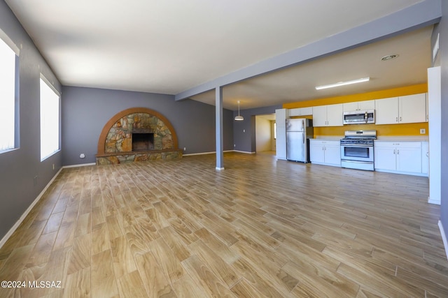 unfurnished living room featuring vaulted ceiling with beams, light hardwood / wood-style flooring, and a stone fireplace