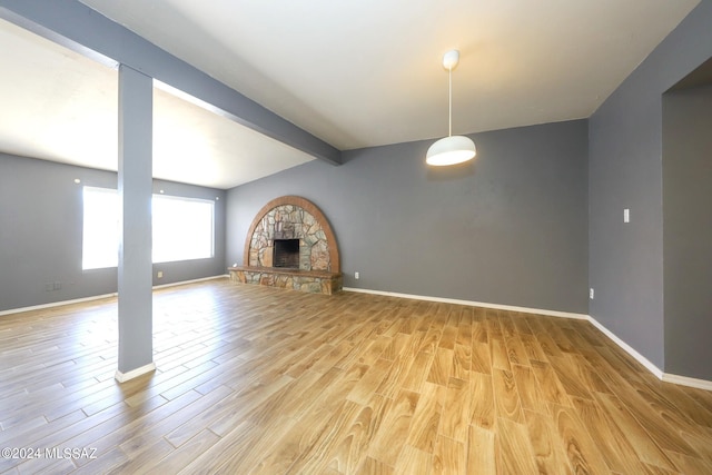 unfurnished living room featuring a fireplace, lofted ceiling with beams, and light wood-type flooring