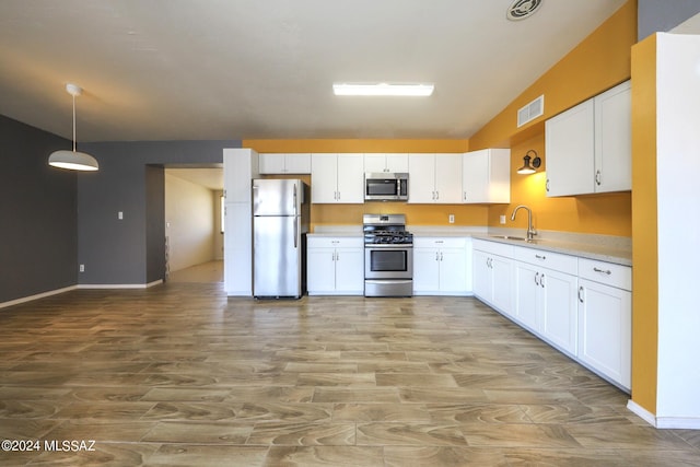 kitchen featuring white cabinets, appliances with stainless steel finishes, decorative light fixtures, and sink