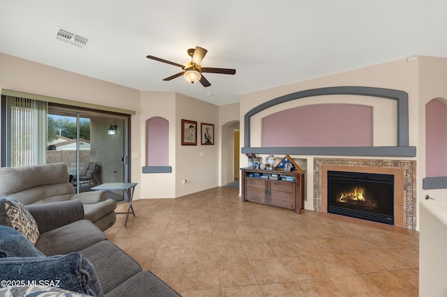 tiled living room with ceiling fan and a fireplace