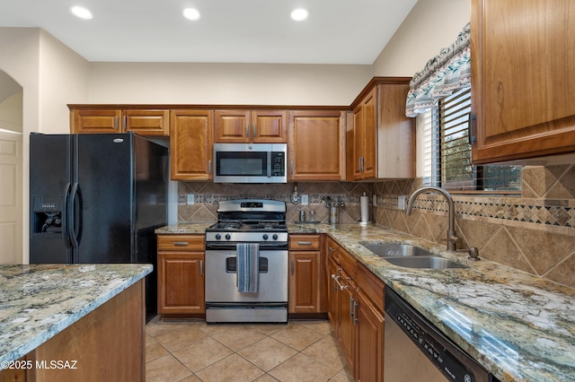 kitchen with stainless steel appliances, sink, backsplash, and light stone counters