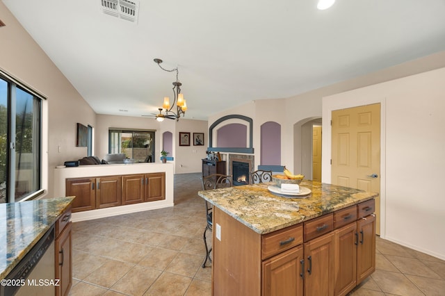 kitchen featuring a breakfast bar area, an inviting chandelier, hanging light fixtures, a kitchen island, and light stone countertops