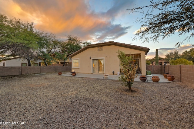 back house at dusk with an outdoor fire pit and a patio