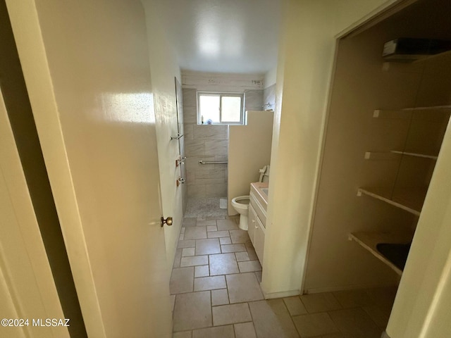 bathroom with tile patterned flooring, a tile shower, and toilet