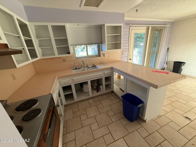 kitchen featuring kitchen peninsula, a wealth of natural light, tile counters, and sink