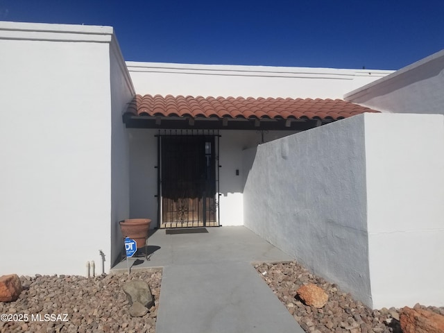 entrance to property with a tiled roof and stucco siding