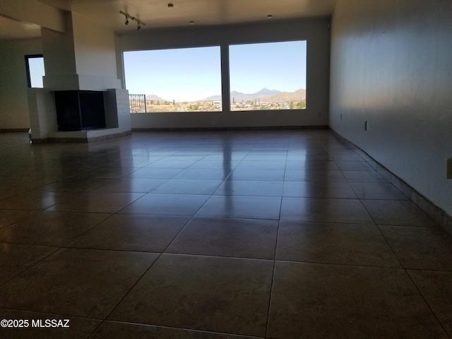 722 N Holm Cir, Nogales, AZ 85621 - unfurnished living room with rail lighting, a mountain view, a wealth of natural light, and dark tile patterned flooring
