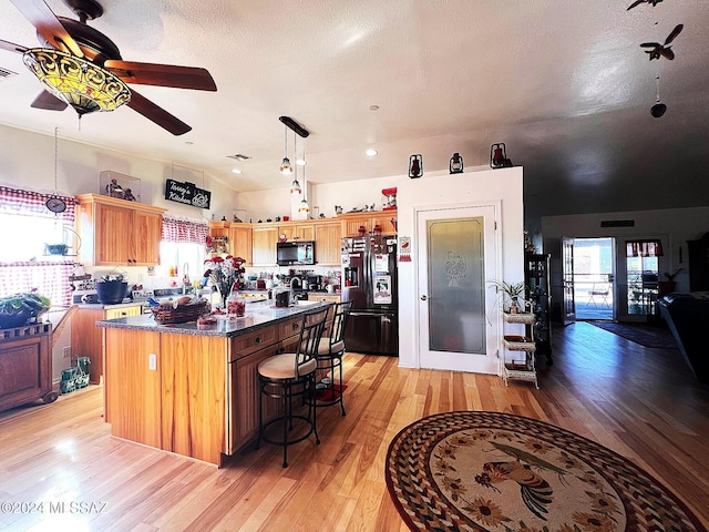 kitchen featuring a center island, black appliances, decorative light fixtures, and light hardwood / wood-style floors