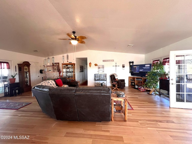 living room with a textured ceiling, light hardwood / wood-style floors, ceiling fan, and lofted ceiling