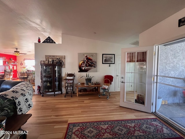 living room with hardwood / wood-style flooring, ceiling fan, and vaulted ceiling