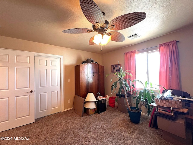 interior space featuring a textured ceiling, carpet floors, and ceiling fan