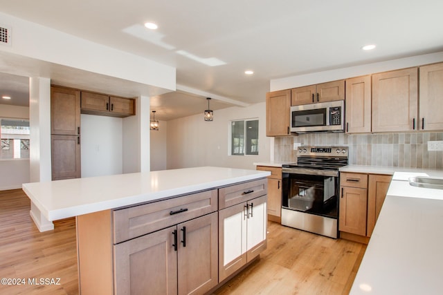 kitchen featuring appliances with stainless steel finishes, backsplash, a center island, light hardwood / wood-style floors, and hanging light fixtures