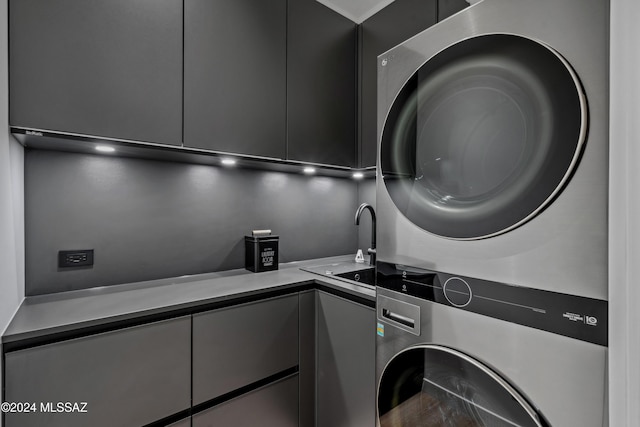 clothes washing area featuring stacked washer and clothes dryer and sink