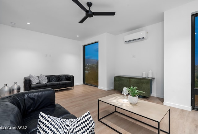 living room with a wall unit AC, light hardwood / wood-style floors, and ceiling fan