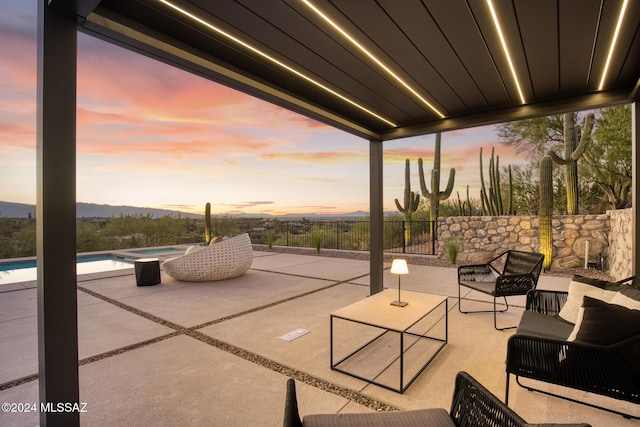 patio terrace at dusk featuring a pool with hot tub