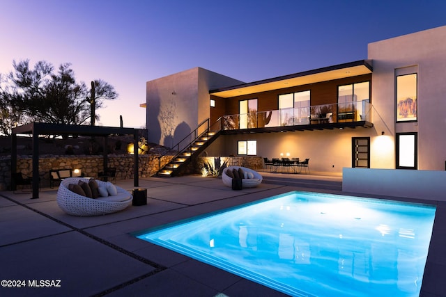 pool at dusk with a patio area