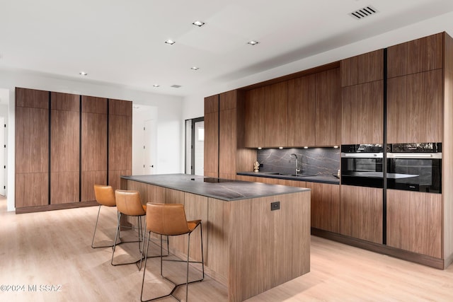 kitchen featuring a kitchen island, sink, oven, and light hardwood / wood-style floors