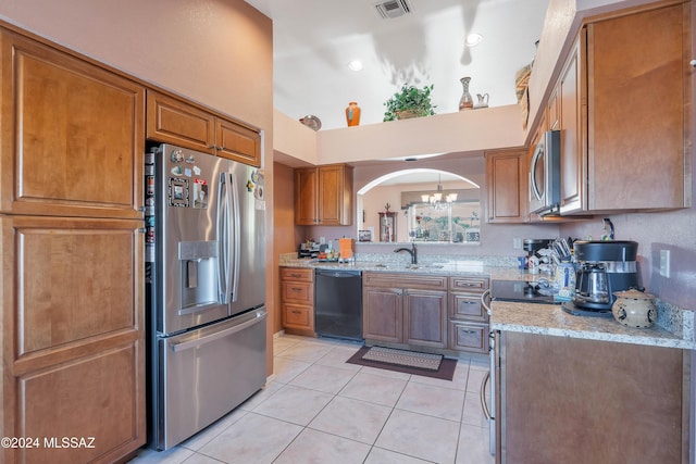 kitchen with a high ceiling, an inviting chandelier, sink, light tile patterned floors, and appliances with stainless steel finishes