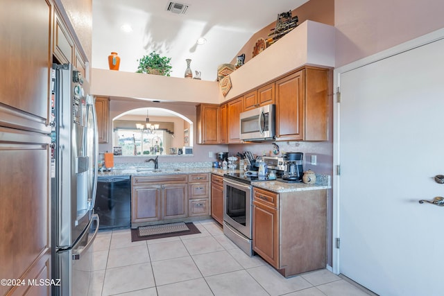 kitchen with light stone countertops, appliances with stainless steel finishes, a notable chandelier, and sink