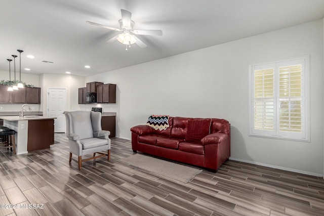 living room featuring ceiling fan, sink, and dark hardwood / wood-style floors