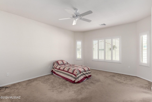 carpeted bedroom with ceiling fan and multiple windows