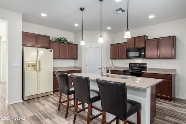 kitchen featuring sink, hanging light fixtures, an island with sink, dark brown cabinets, and black appliances