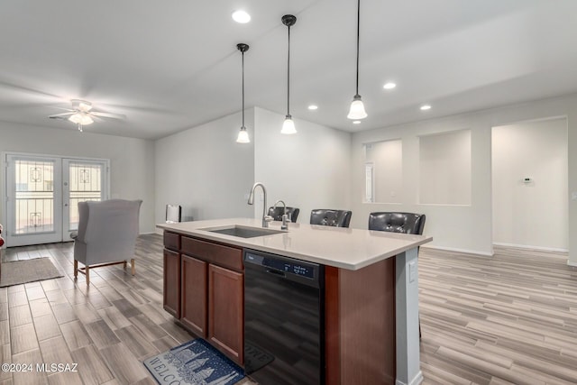 kitchen with sink, pendant lighting, light hardwood / wood-style flooring, dishwasher, and an island with sink