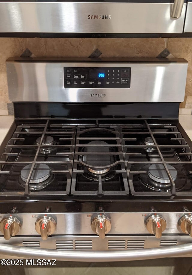 interior details featuring decorative backsplash and stainless steel gas range