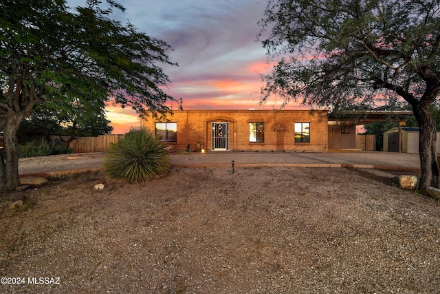 pueblo-style home featuring an outdoor structure, fence, a carport, and a storage unit