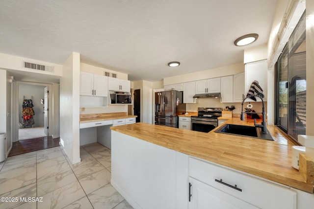 kitchen featuring appliances with stainless steel finishes, butcher block counters, visible vents, and a sink