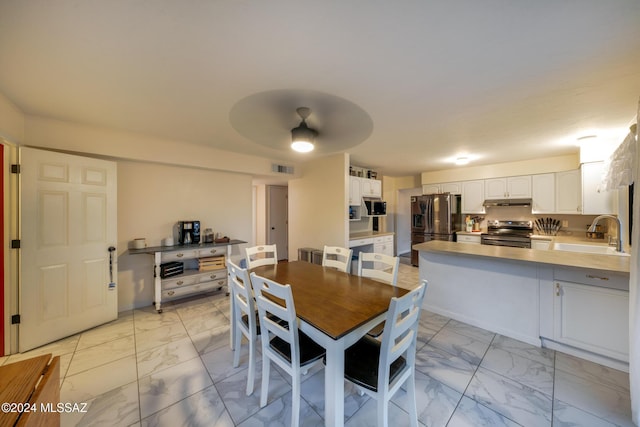 dining space featuring ceiling fan and sink