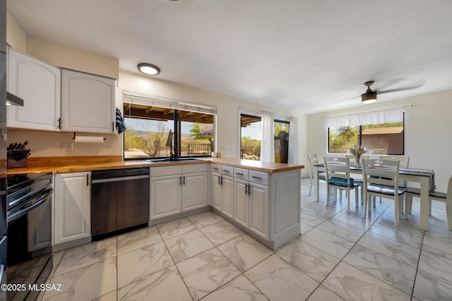 kitchen featuring dishwasher, marble finish floor, a peninsula, and a sink