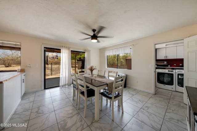 dining room featuring washing machine and dryer, marble finish floor, baseboards, and ceiling fan