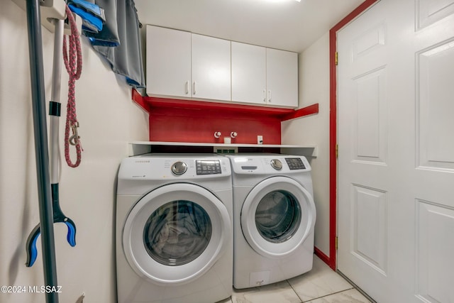 washroom with cabinets, light tile patterned floors, and washing machine and clothes dryer