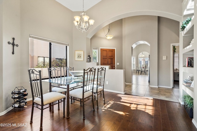 dining area with a notable chandelier, a high ceiling, and dark wood-type flooring