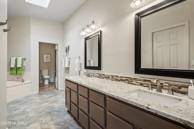 bathroom featuring toilet, a skylight, decorative backsplash, a tub to relax in, and vanity