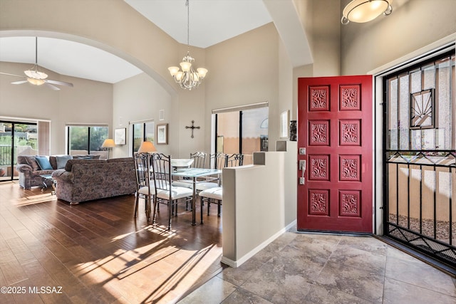 foyer entrance featuring high vaulted ceiling and ceiling fan with notable chandelier