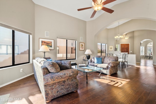 living room featuring ceiling fan with notable chandelier, dark wood-type flooring, and high vaulted ceiling