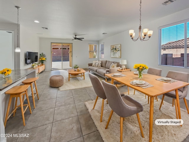 dining area with ceiling fan with notable chandelier and tile patterned floors