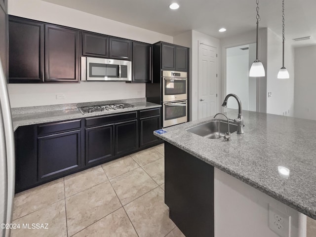 kitchen featuring sink, light stone countertops, light tile patterned floors, decorative light fixtures, and stainless steel appliances