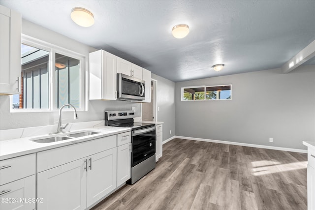 kitchen featuring a textured ceiling, stainless steel appliances, sink, light hardwood / wood-style flooring, and white cabinetry