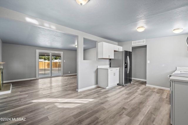 kitchen featuring white cabinets, stainless steel refrigerator with ice dispenser, light hardwood / wood-style floors, and range