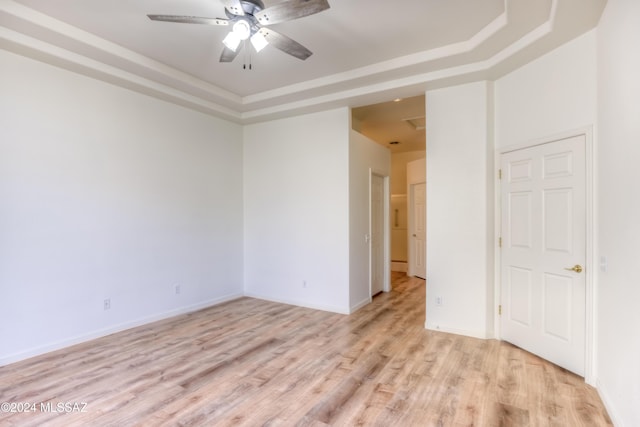 empty room with a tray ceiling, ceiling fan, and light wood-type flooring