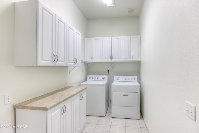 laundry area featuring cabinets, light tile patterned floors, and washer and dryer