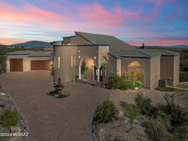 view of front of home featuring decorative driveway, a mountain view, an attached garage, and stucco siding