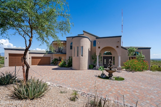 mediterranean / spanish-style house featuring a garage, french doors, decorative driveway, and stucco siding