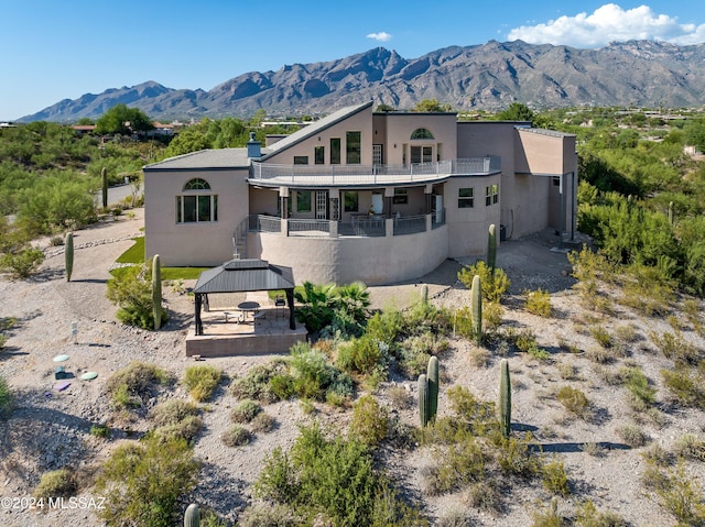 rear view of house with a gazebo, a mountain view, and a balcony