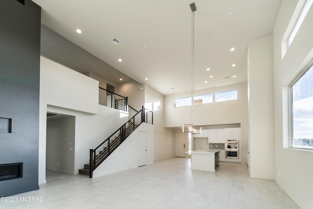 unfurnished living room with a fireplace, a high ceiling, and sink